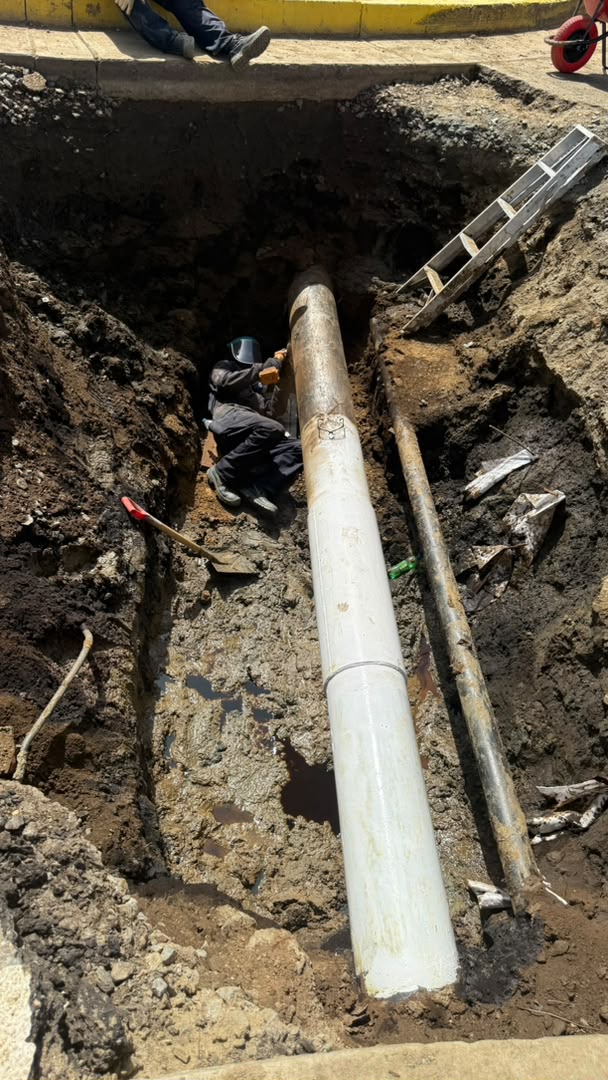 Tubería en una zanja con un soldador trabajando